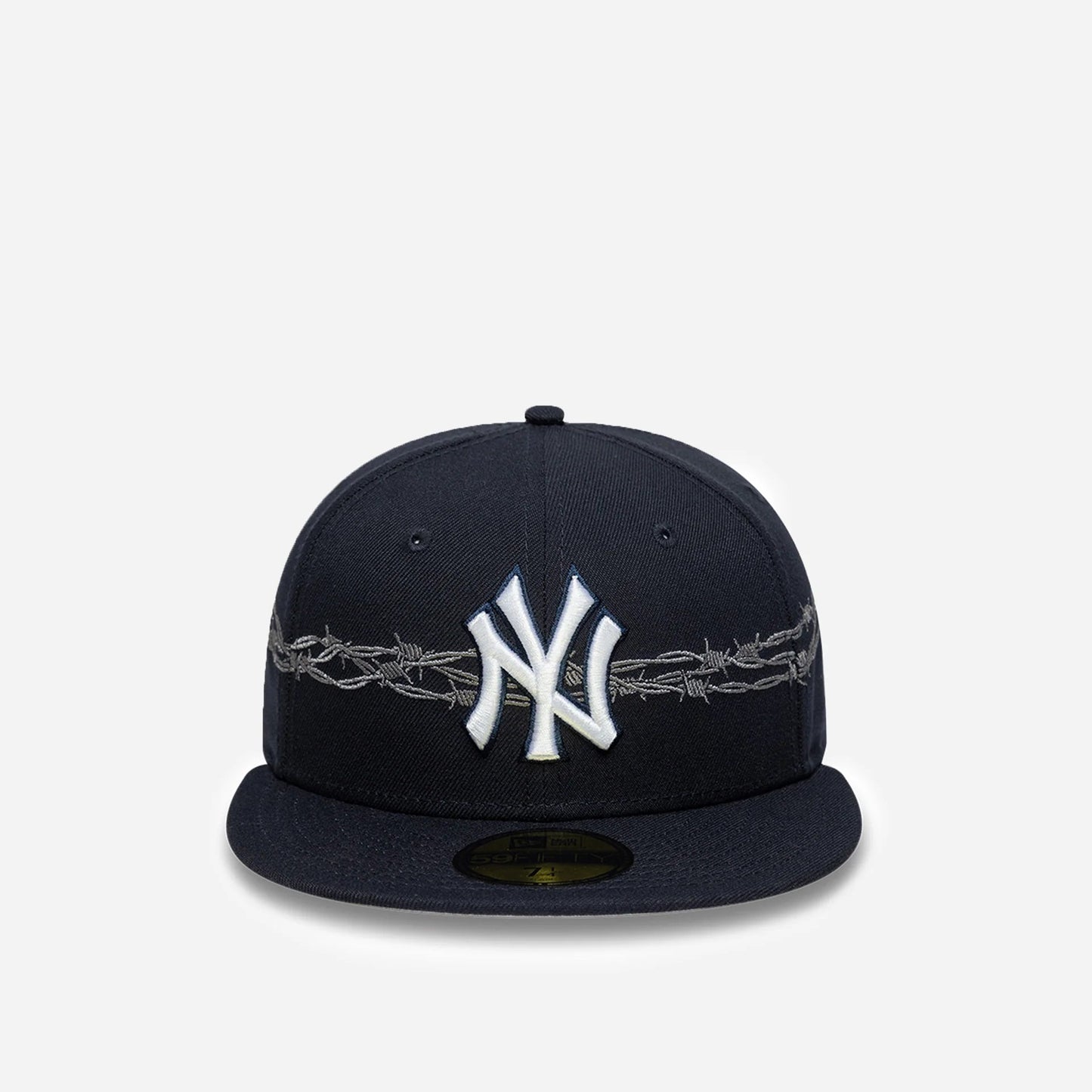 A navy blue New York Yankees fitted cap featuring a white embroidered NY logo on the front, with a silver barbed wire design wrapping around the crown, set against a light gray background.